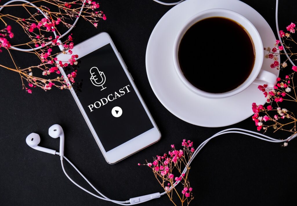 Mobile phone podcast with headphones on workplace. Listening to podcast. Audiobook. Online education