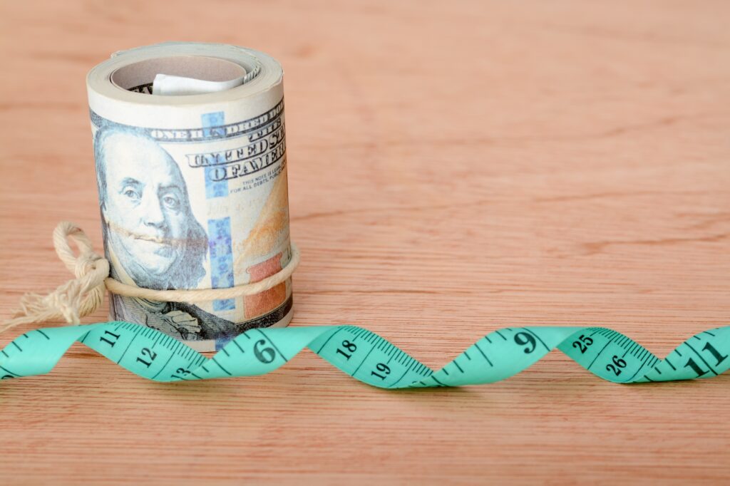 Money banknotes and green measuring tape. Expense for diet, weight loss and fasting concept